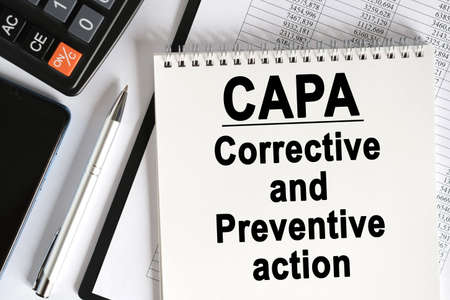 On the table lies a smartphone, a calculator and a notebook with the inscription- CAPA. Corrective and Preventive action. Business conceptの写真素材