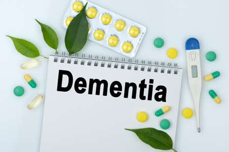 On the table are pills, a thermometer, leaves and a notebook with the inscription -Dementia. The concept of medicine.の写真素材