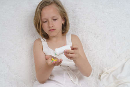 Sick teenage girl spills pills on her hand. Medical concept.の写真素材