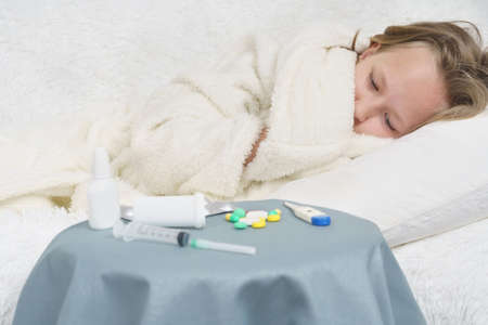 A sick teenage girl takes pills and drinks them with water. Medical concept.の写真素材