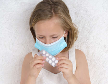 A sick teenage girl takes pills and drinks them with water. Medical concept.の写真素材
