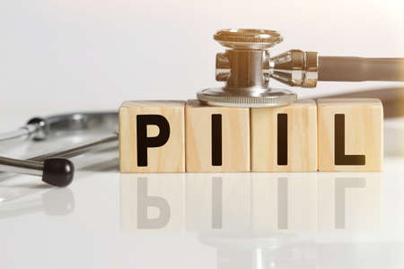 PILL the word on wooden cubes, cubes stand on a reflective white surface, on cubes - a stethoscope. Medicine conceptの写真素材