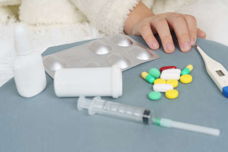 A girl takes a thermometer from the table where the medicines are. Medical concept.の写真素材