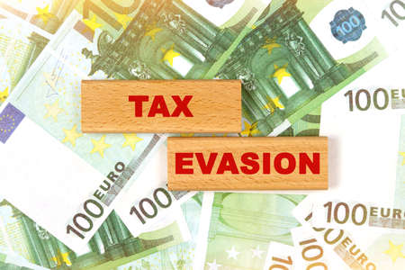 Business concept. Against the background of euro bills, the text is written on wooden blocks - tax evasionの写真素材