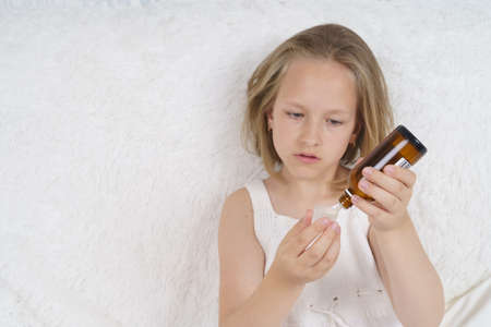 Sick teenager girl pours medicine from a jar. Medical concept.の写真素材