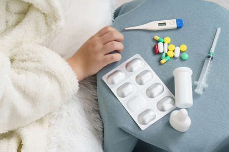 A girl takes a thermometer from the table where the medicines are. Medical concept.の写真素材