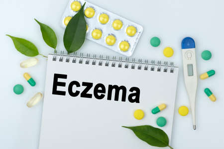 On the table are pills, a thermometer, leaves and a notebook with the inscription -Eczema. The concept of medicine.の写真素材