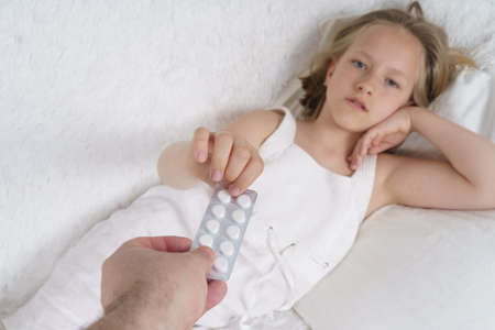 A sick teenage girl measures the temperature, next to her is a cat. Medical concept.の写真素材