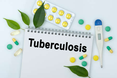 On the table are pills, a thermometer, leaves and a notebook with the inscription -Tuberculosis. The concept of medicine.の写真素材