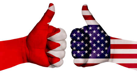 The concept of strengthening the relationship of nations. Two hands are painted with flags of different countries, with a thumb raised up. Bahrain and the USAの写真素材