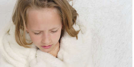 Sick teenage girl in a protective mask, next to her is a cat. Medical concept.の写真素材