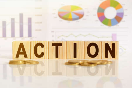 ACTION the word on wooden cubes, cubes stand on a reflective surface, in the background is a business diagram. Business and finance conceptの写真素材