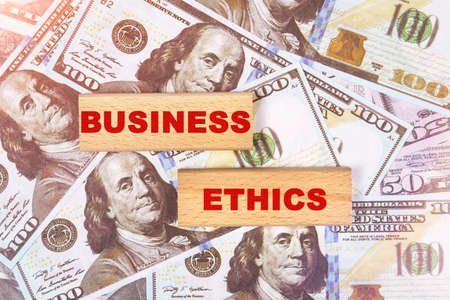 Business concept. Against the background of dollar bills, the text is written on wooden blocks - business ethicsの写真素材