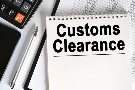 On the table lies a smartphone, a calculator and a notebook with the inscription- Customs Clearance. Business conceptの写真素材