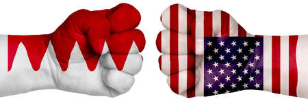 The concept of the struggle of peoples. Two hands are clenched into fists and are located opposite each other. Hands painted in the colors of the flags of the countries. Bahrain vs USAの写真素材