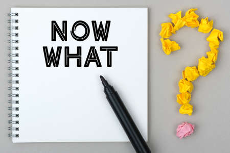Hand with marker writing: Now What. Notepad and question mark.の写真素材