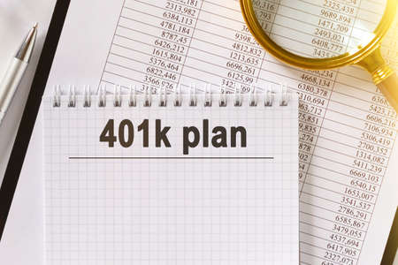 On the table are financial reports, a pen, a magnifying glass and a notebook with the inscription - plan 401k. Business and finance concept.の写真素材