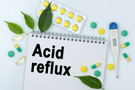 On the table are pills, a thermometer, leaves and a notebook with the inscription -Acid reflux. The concept of medicine.の写真素材