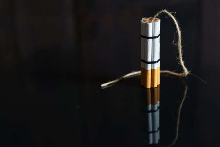 The concept of medicine is the fight against smoking. Cigarettes are twisted into a dynamite checker with a filament on a black reflective surface.の写真素材