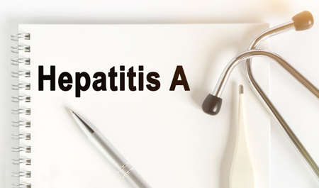 On the table are a stethoscope, a thermometer, a pen and a notebook with the inscription -Hepatitis A. The concept of medicine.の写真素材