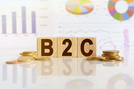 Business to consumer. B2C the word on wooden cubes, cubes stand on a reflective surface, in the background is a business diagram. Business and finance conceptの写真素材
