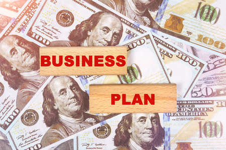Business concept. Against the background of dollar bills, the text is written on wooden blocks - business planの写真素材