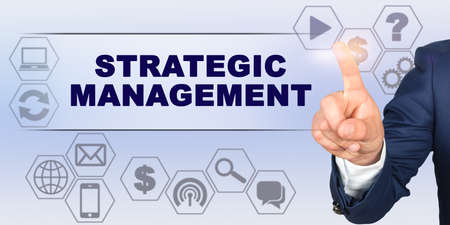Business concept. Businessman touching virtual screen with his finger. Screen caption - STRATEGIC MANAGEMENTの写真素材