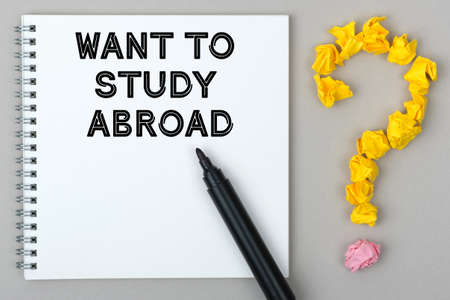 Hand with marker writing: Want to Study Abroad. Notepad and question mark.の写真素材