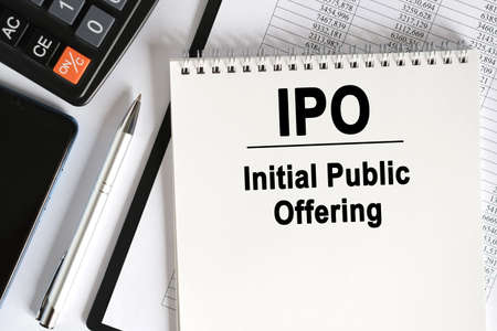 On the table lies a smartphone, a calculator and a notebook with the inscription- IPO. Initial Public Offering. Business conceptの写真素材