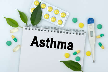 On the table are pills, a thermometer, leaves and a notebook with the inscription -Asthma. The concept of medicine.の写真素材