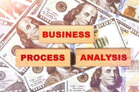 Business concept. Against the background of dollar bills, the text is written on wooden blocks - business process analysisの写真素材