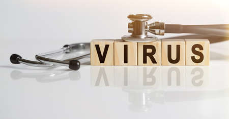 VIRUS the word on wooden cubes, cubes stand on a reflective white surface, on cubes - a stethoscope. Medicine conceptの写真素材