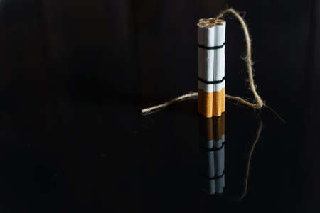 The concept of medicine is the fight against smoking. Cigarettes are twisted into a dynamite checker with a filament on a black reflective surface.の写真素材