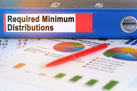 On the table are pie charts, a pen and a folder with the inscription - Required Minimum Distributions. Business and finance concept.の写真素材