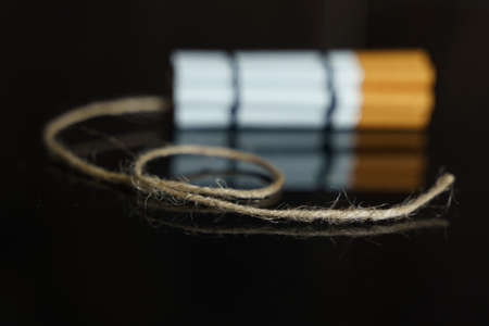The concept of medicine is the fight against smoking. Cigarettes are twisted into a dynamite checker with a filament on a black reflective surface.の写真素材