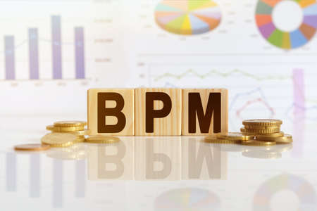Business process management. BPM the word on wooden cubes, cubes stand on a reflective surface, in the background is a business diagram. Business and finance conceptの写真素材