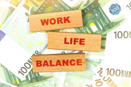 Business concept. Against the background of euro bills, the text is written on wooden blocks - work life balanceの写真素材