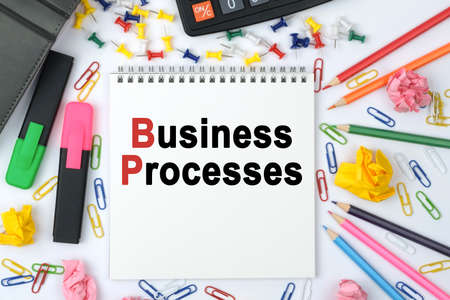 Business concept. On the table is a calculator, diary, markers, pencils and a notebook with the inscription - Business Processesの写真素材