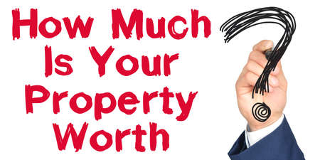 Hand with marker writing: How Much Is Your Property Worth. Hand of a businessman with a marker.の写真素材