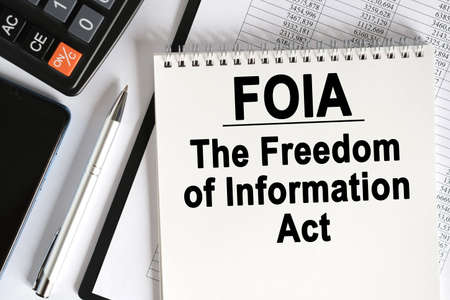 On the table lies a smartphone, a calculator and a notebook with the inscription- FOIA. The Freedom of Information Act. Business conceptの写真素材