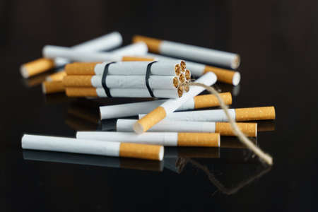 The concept of medicine is the fight against smoking. Cigarettes, in the form of sticks of dynamite, lie among the scattered cigarettes on a black reflective surface.の写真素材