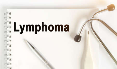 On the table are a stethoscope, a thermometer, a pen and a notebook with the inscription -Lymphoma. The concept of medicine.の写真素材