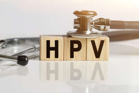 HPV the word on wooden cubes, cubes stand on a reflective white surface, on cubes - a stethoscope. Medicine conceptの写真素材
