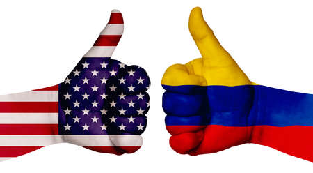The concept of strengthening the relationship of nations. Two hands are painted with flags of different countries, with a thumb raised up. Colombia and the usaの写真素材