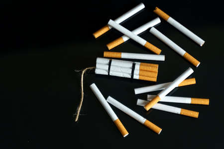 The concept of medicine is the fight against smoking. Cigarettes, in the form of sticks of dynamite, lie among the scattered cigarettes on a black reflective surface.の写真素材