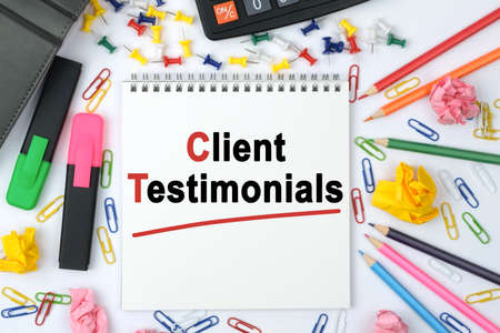 Business concept. On the table is a calculator, diary, markers, pencils and a notebook with the inscription - Client Testimonialsの写真素材