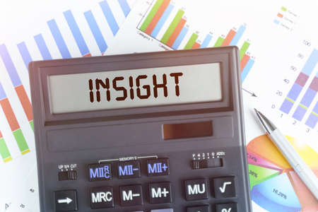 The concept of business and finance. On the table are financial charts and a calculator, on the electronic board of which is written the text - INSIGHTの写真素材