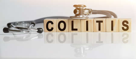 COLITIS the word on wooden cubes, cubes stand on a reflective white surface, on cubes - a stethoscope. Medicine conceptの写真素材