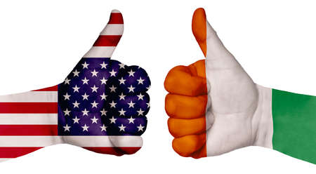 The concept of strengthening the relationship of nations. Two hands are painted with flags of different countries, with a thumb raised up. Cote D Ivoire and the USAの写真素材
