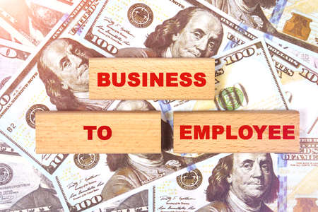 Business concept. Against the background of dollar bills, the text is written on wooden blocks - business to employeeの写真素材